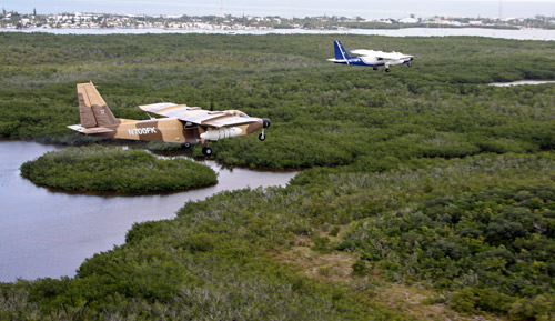 Two planes applying an aerial insecticide treatment to a marsh. 
